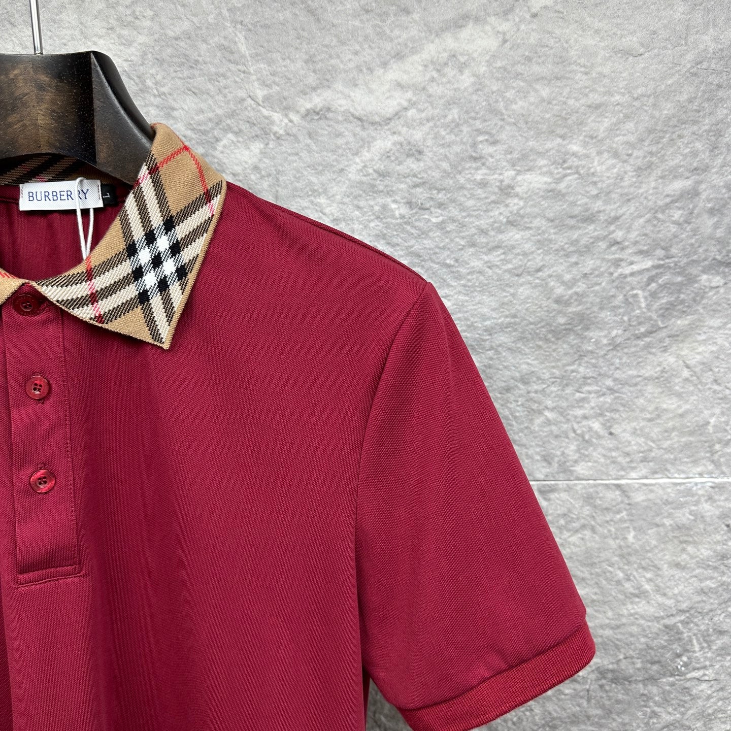 Maroon polo shirt shoulder and collar with Burberry check trim.