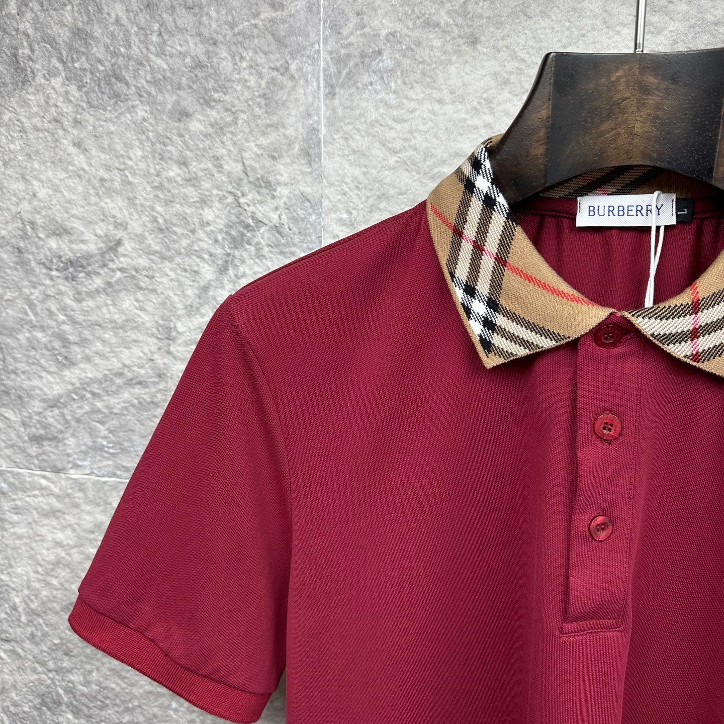 Maroon polo shirt detail: check-pattern collar and three-button placket.