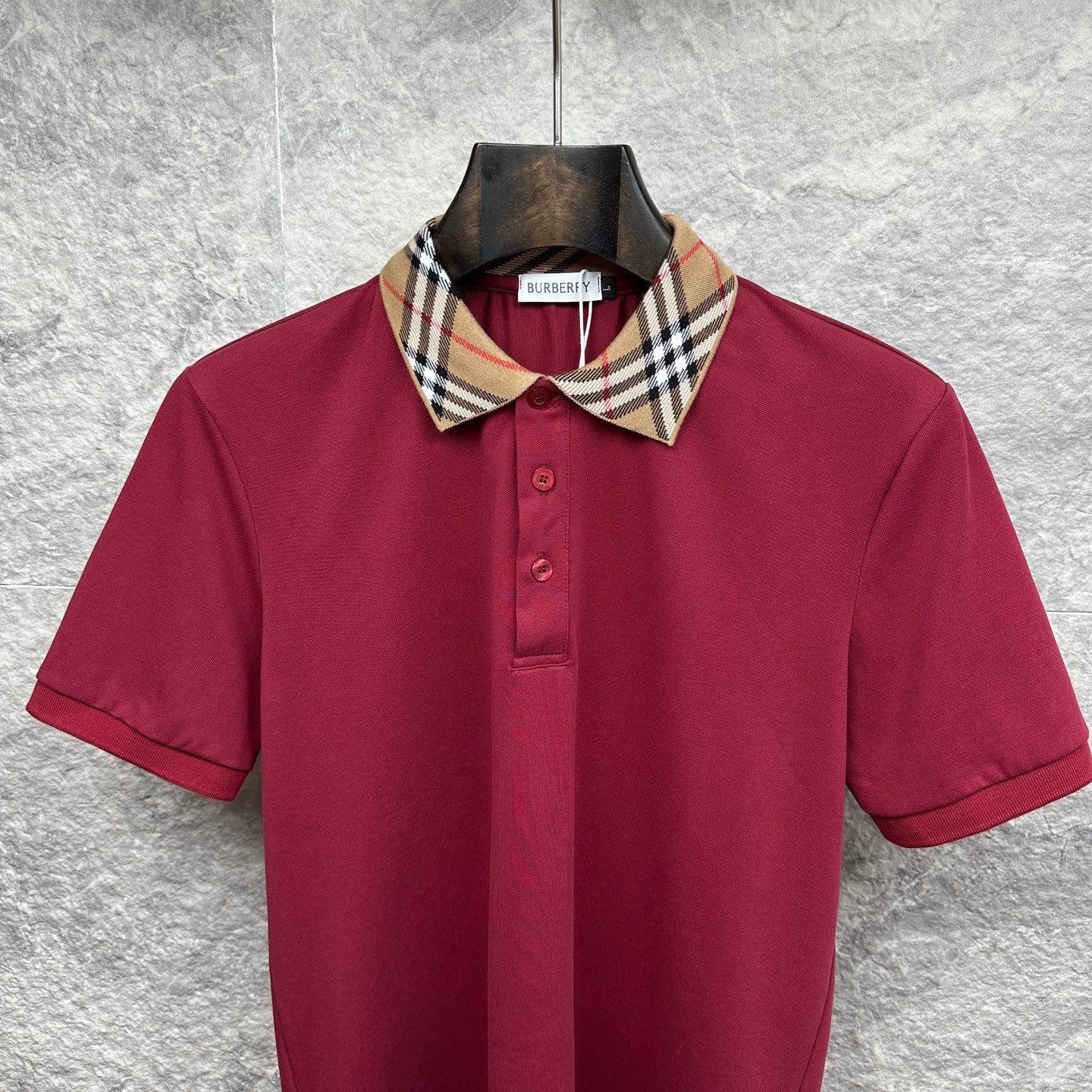 Maroon Burberry polo shirt with check collar, short sleeves, and button placket.