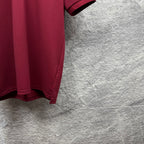 Maroon polo shirt sleeve cuff and side hem detail.