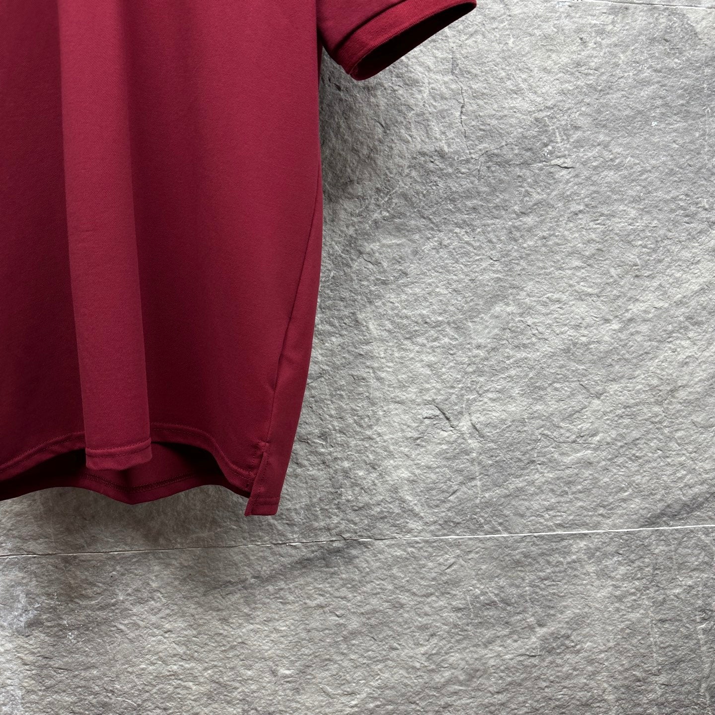 Maroon polo shirt sleeve cuff and side hem detail.