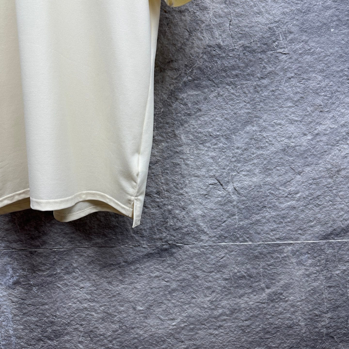 Cream polo shirt hem with side slit detail, hanging