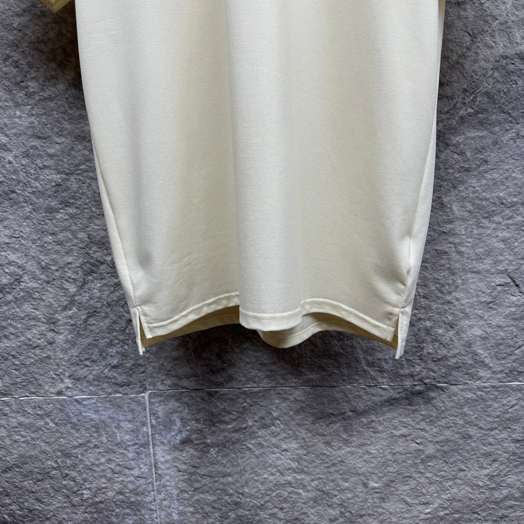 Cream polo shirt with curved hem and side vent, hanging
