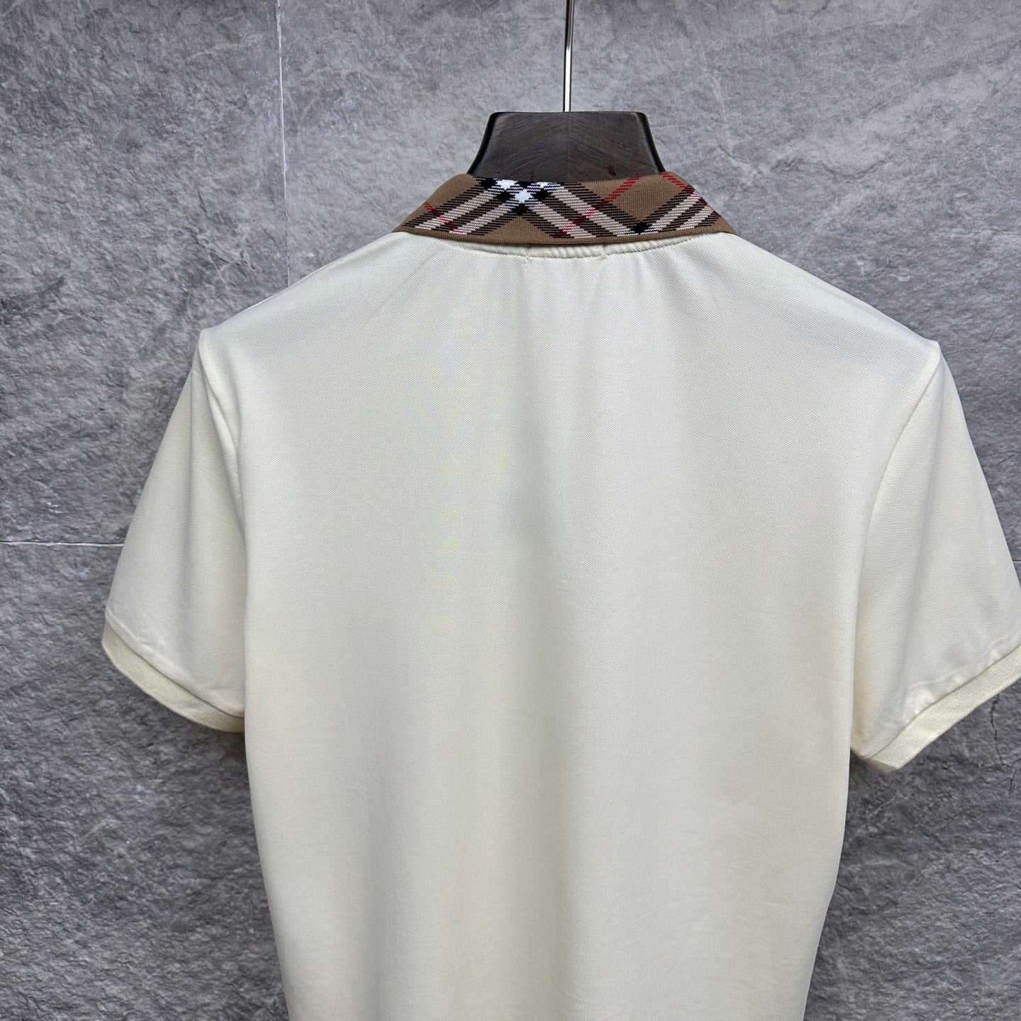 Cream polo shirt back with check-trim collar, hanging