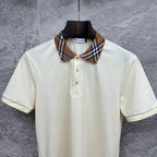 Cream polo shirt with Burberry check collar, three-button placket, on hanger