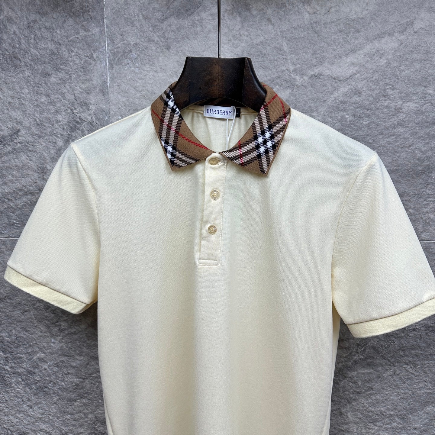 Cream polo shirt with Burberry check collar, three-button placket, on hanger