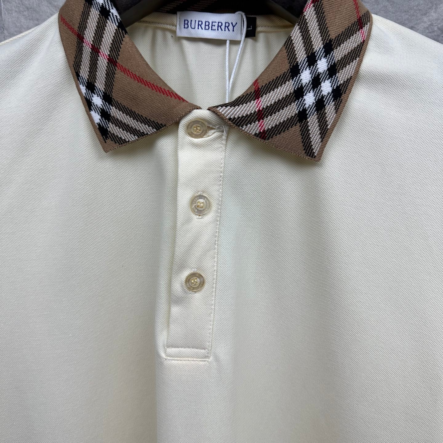 Cream polo shirt close-up of check collar and three button placket