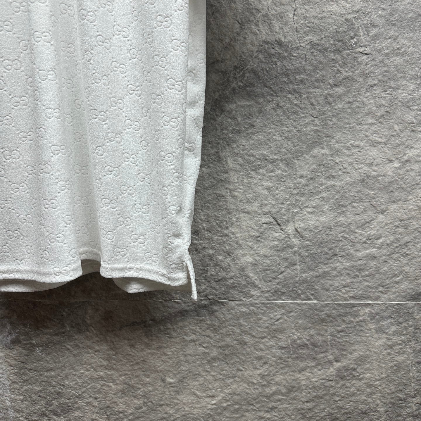 Gucci white polo shirt with embossed GG pattern and curved side hem.