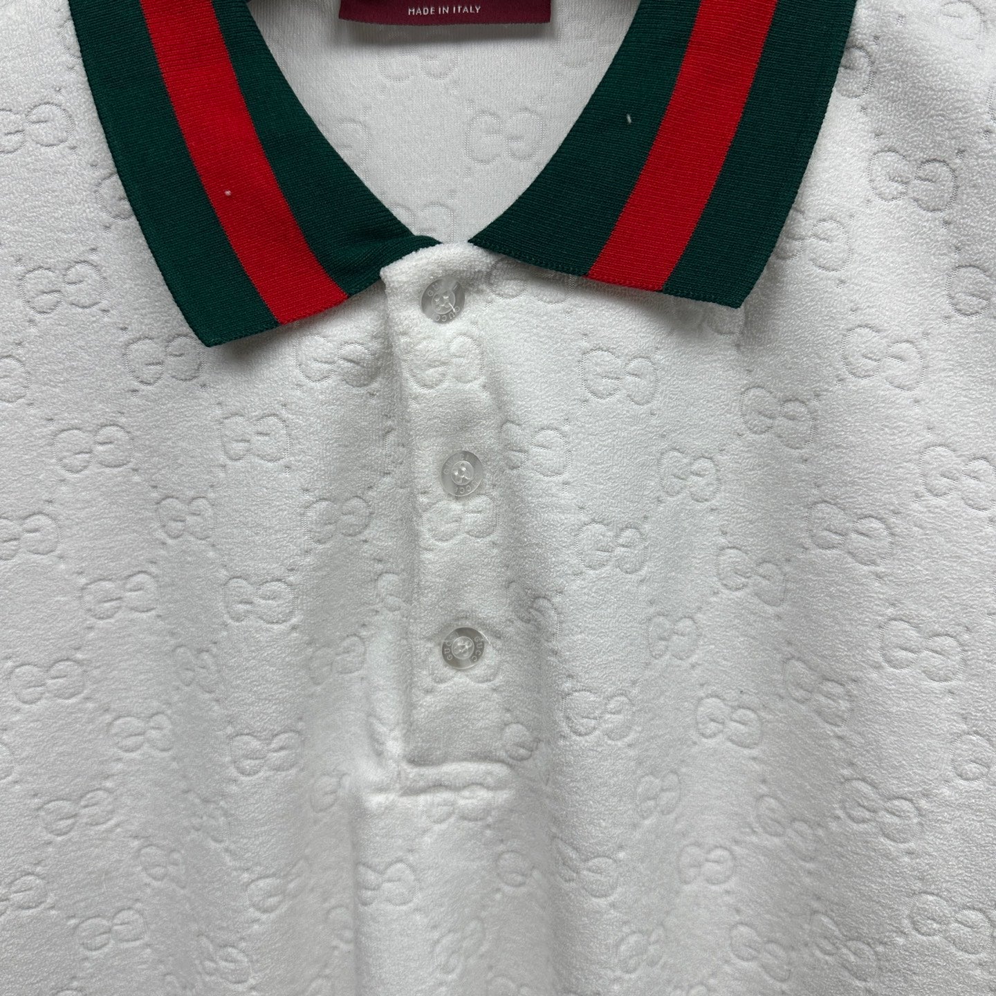Gucci white polo shirt close-up with green-red striped collar and button placket.