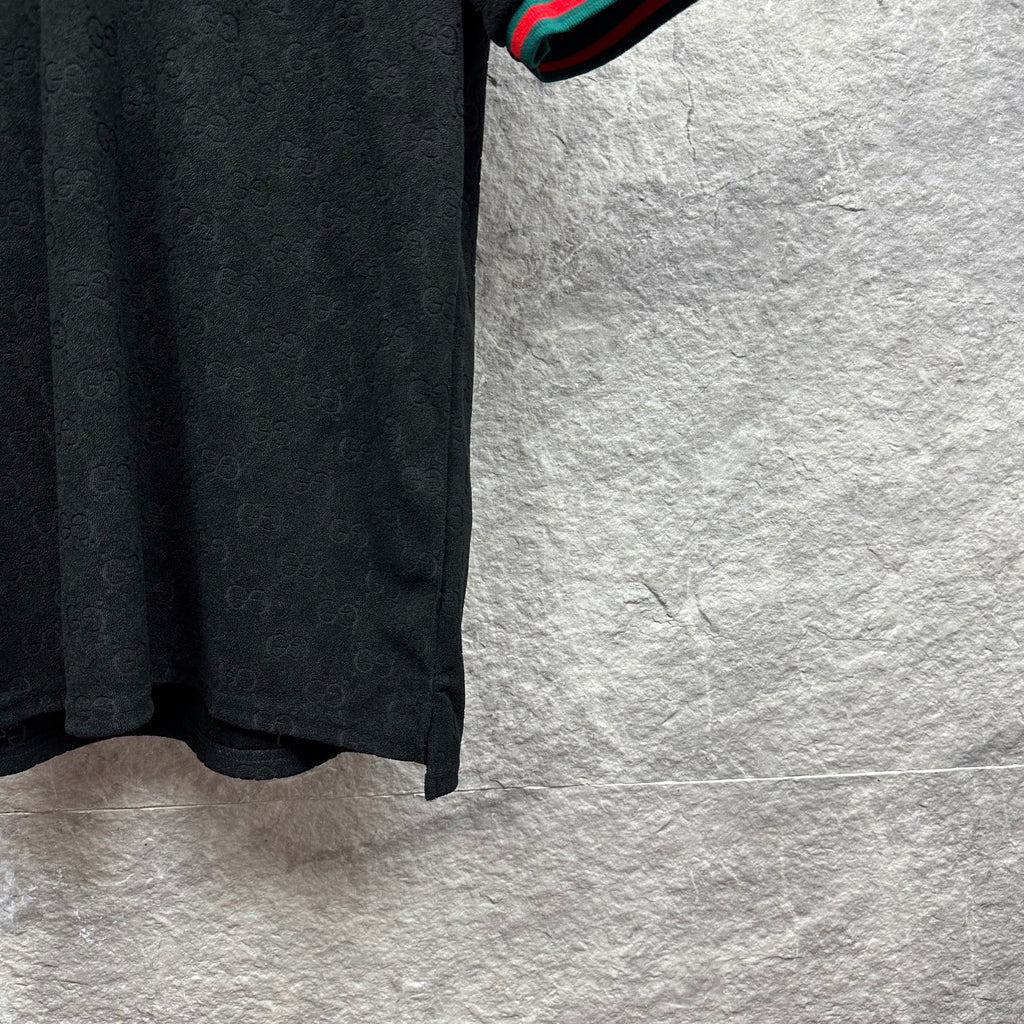 Gucci dark polo shirt side view with monogram pattern and striped cuff edge