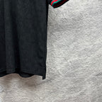 Gucci dark polo shirt side view with monogram pattern and striped cuff edge