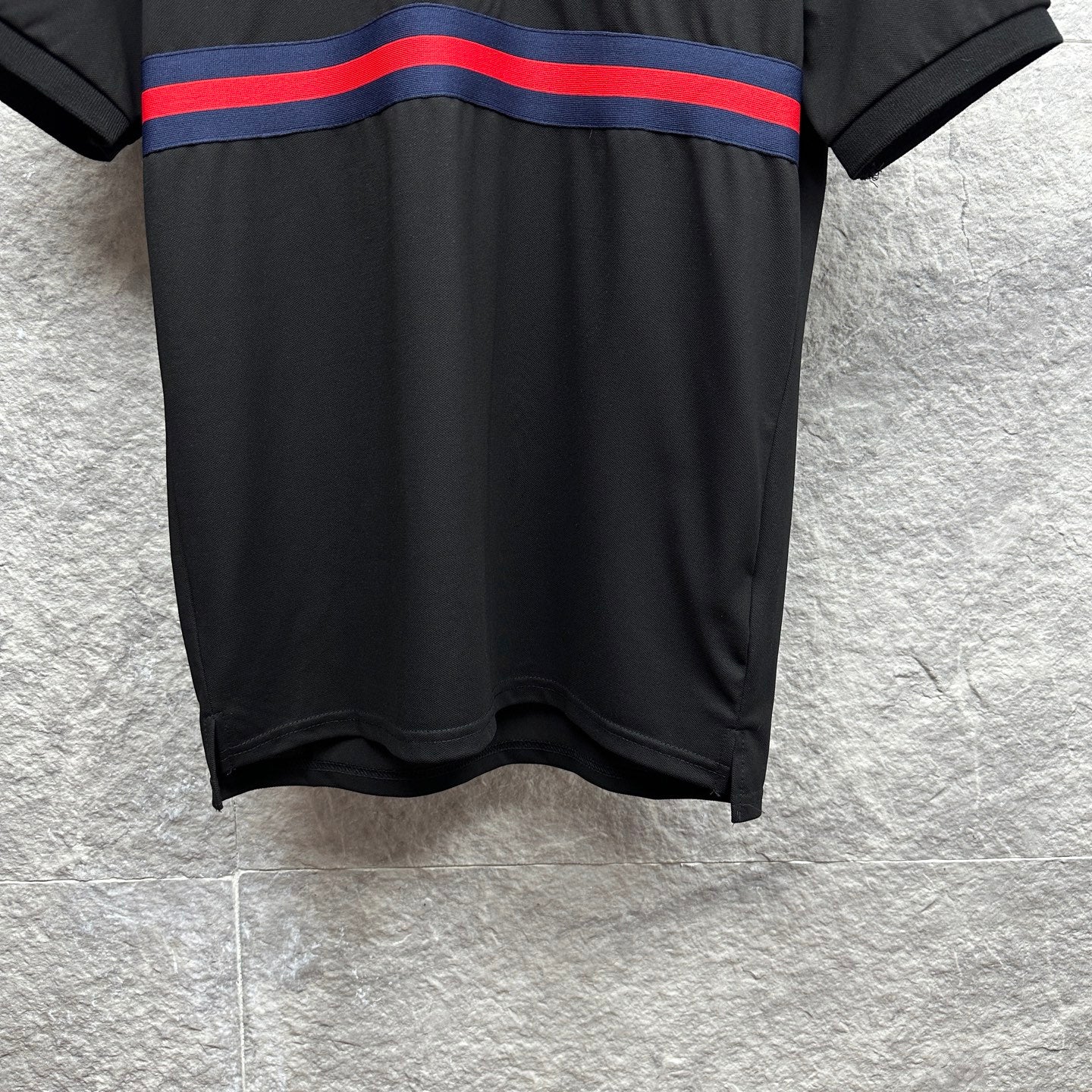 Black Gucci polo shirt hem and striped chest band visible on front.