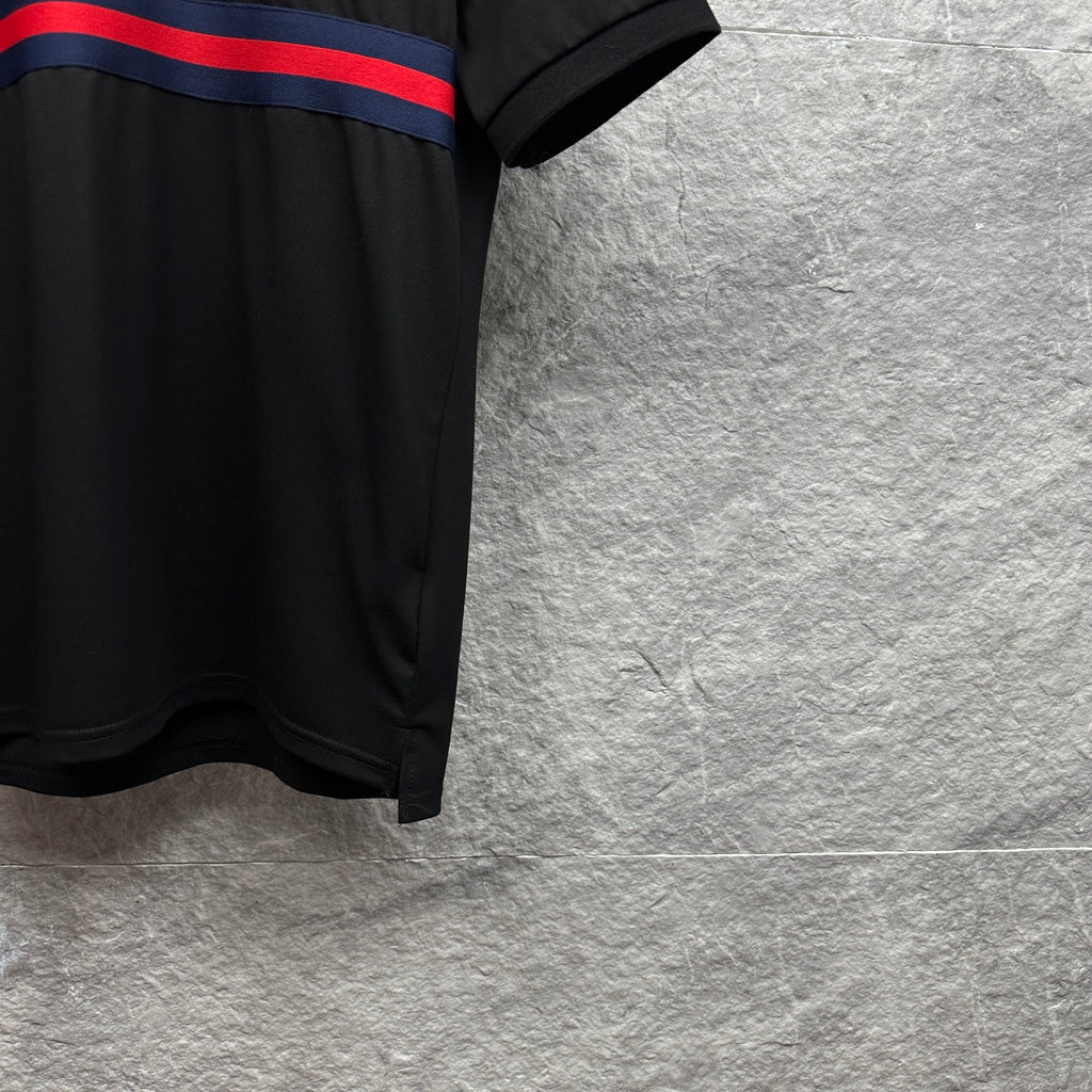 Black Gucci polo shirt side hem with blue-red striped band at chest.