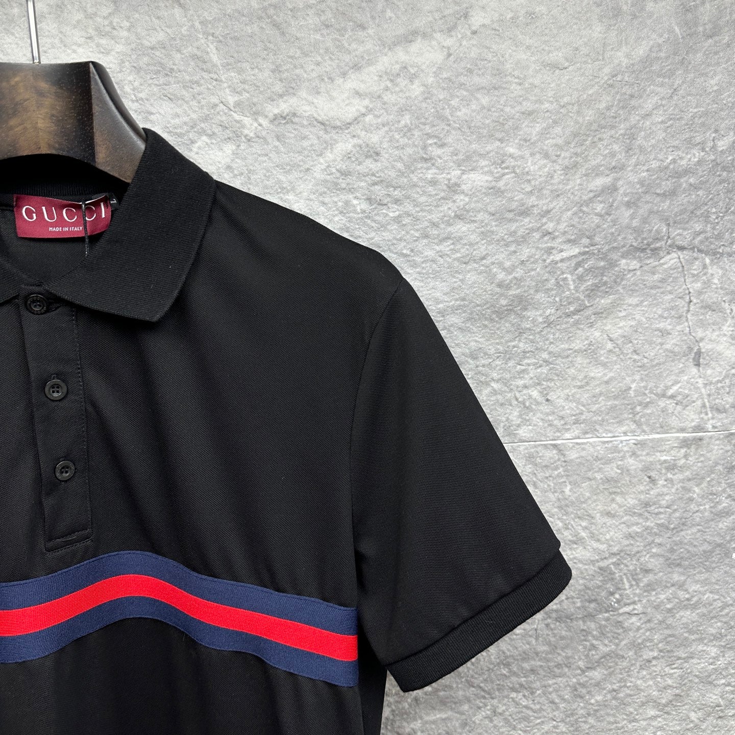 Black Gucci polo shirt shoulder and collar detail with striped chest band.