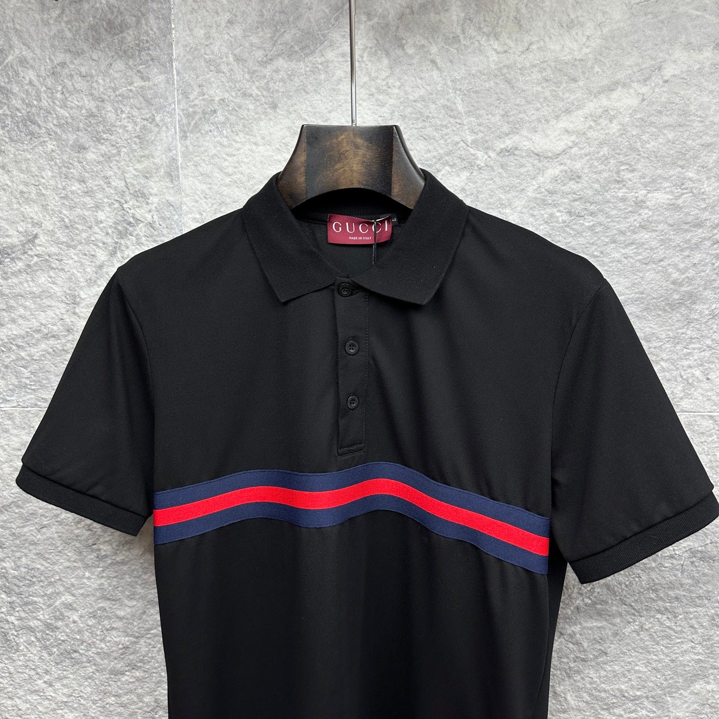 Black Gucci polo with buttoned placket and blue-red striped chest band.