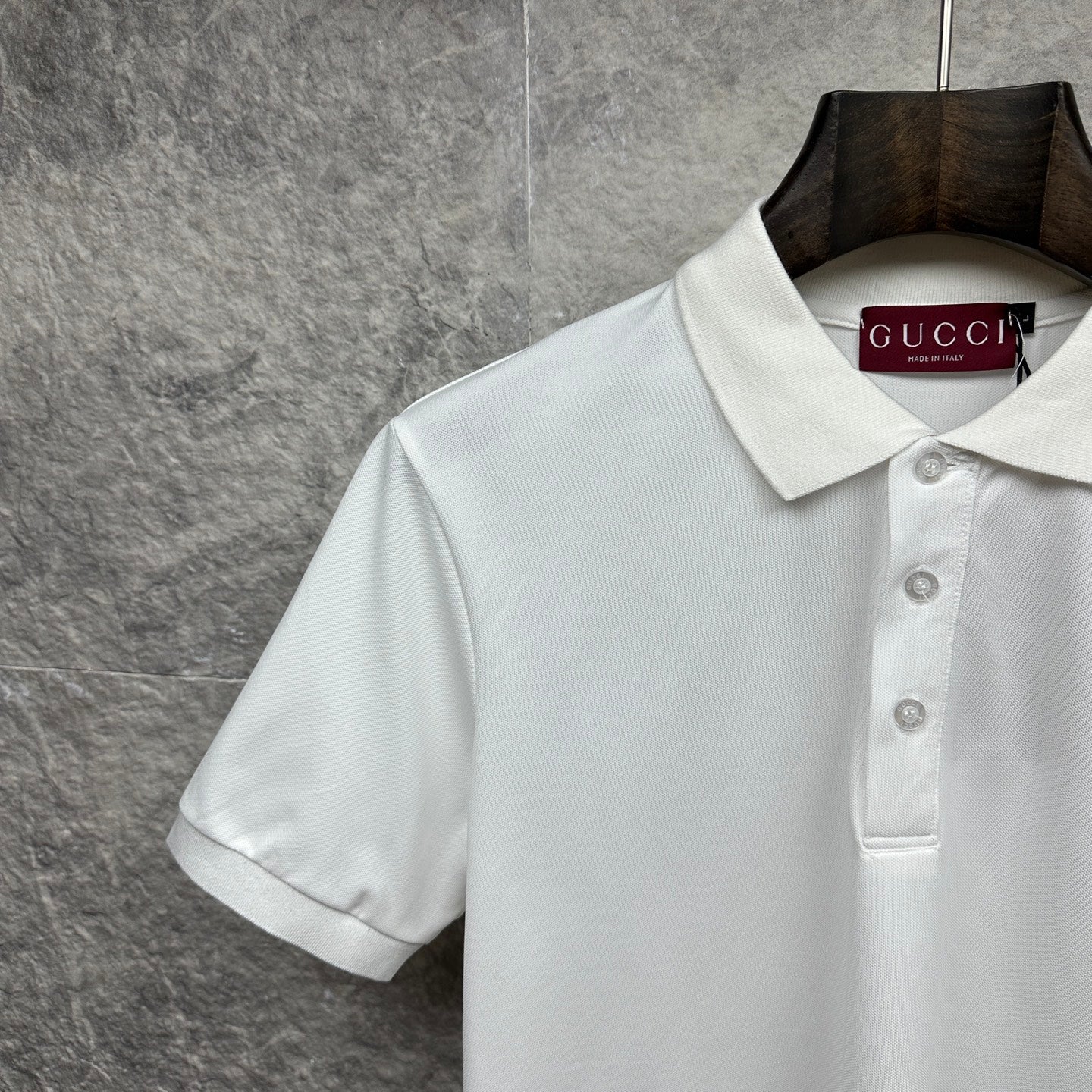 White Gucci polo shirt close-up of collar, buttons, and chest logo
