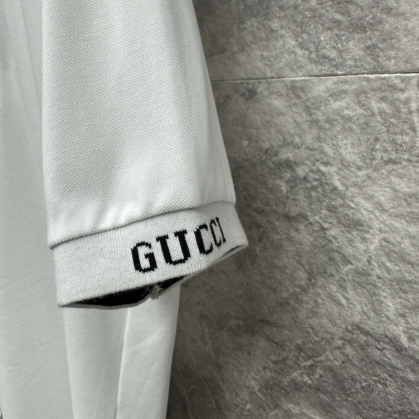 White Gucci polo shirt sleeve cuff with GUCCI embroidered band