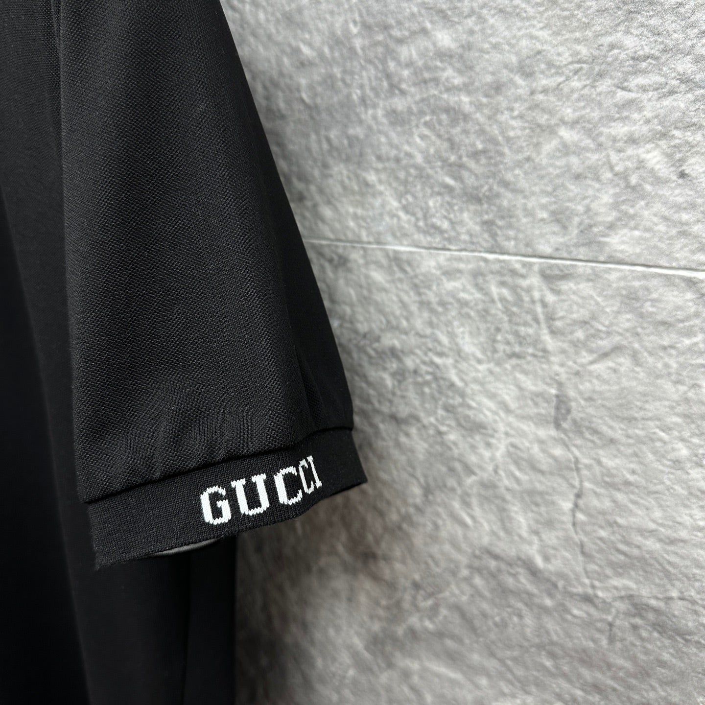 Black Gucci polo shirt sleeve cuff with GUCCI logo detail