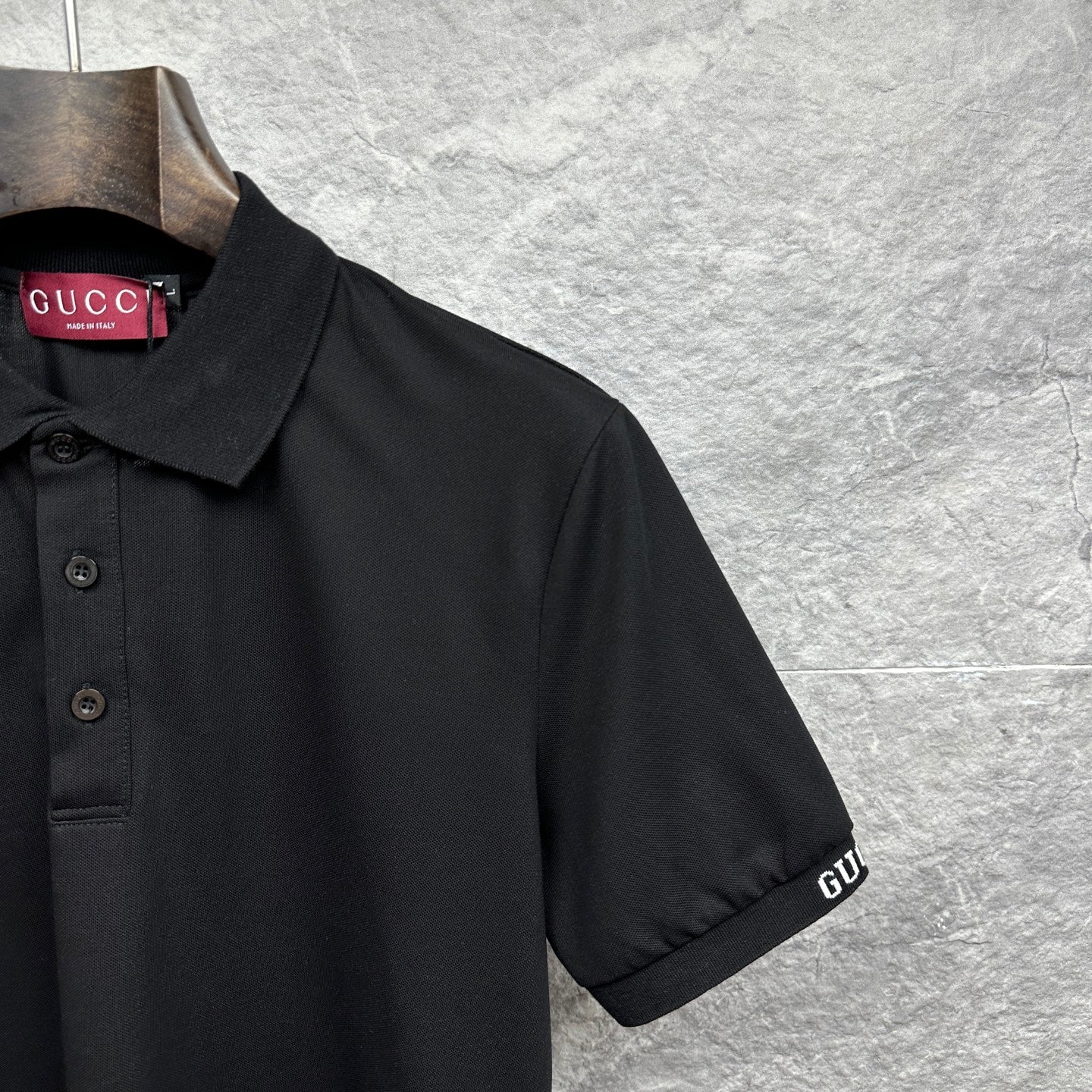 Black Gucci polo shirt sleeve with stitched GUCCI logo cuff