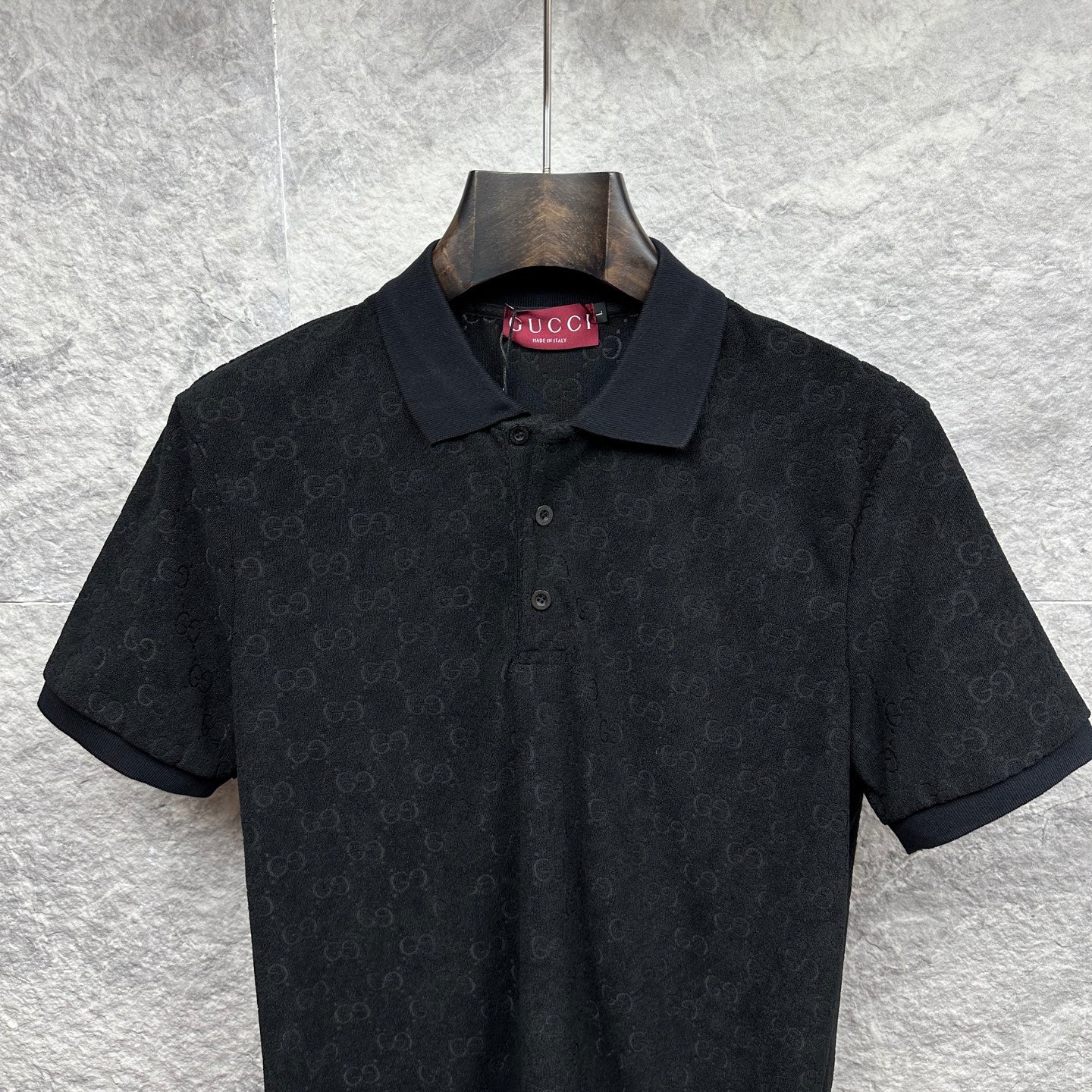 Black Gucci polo shirt with collar and buttons, short sleeves, subtle GG monogram.