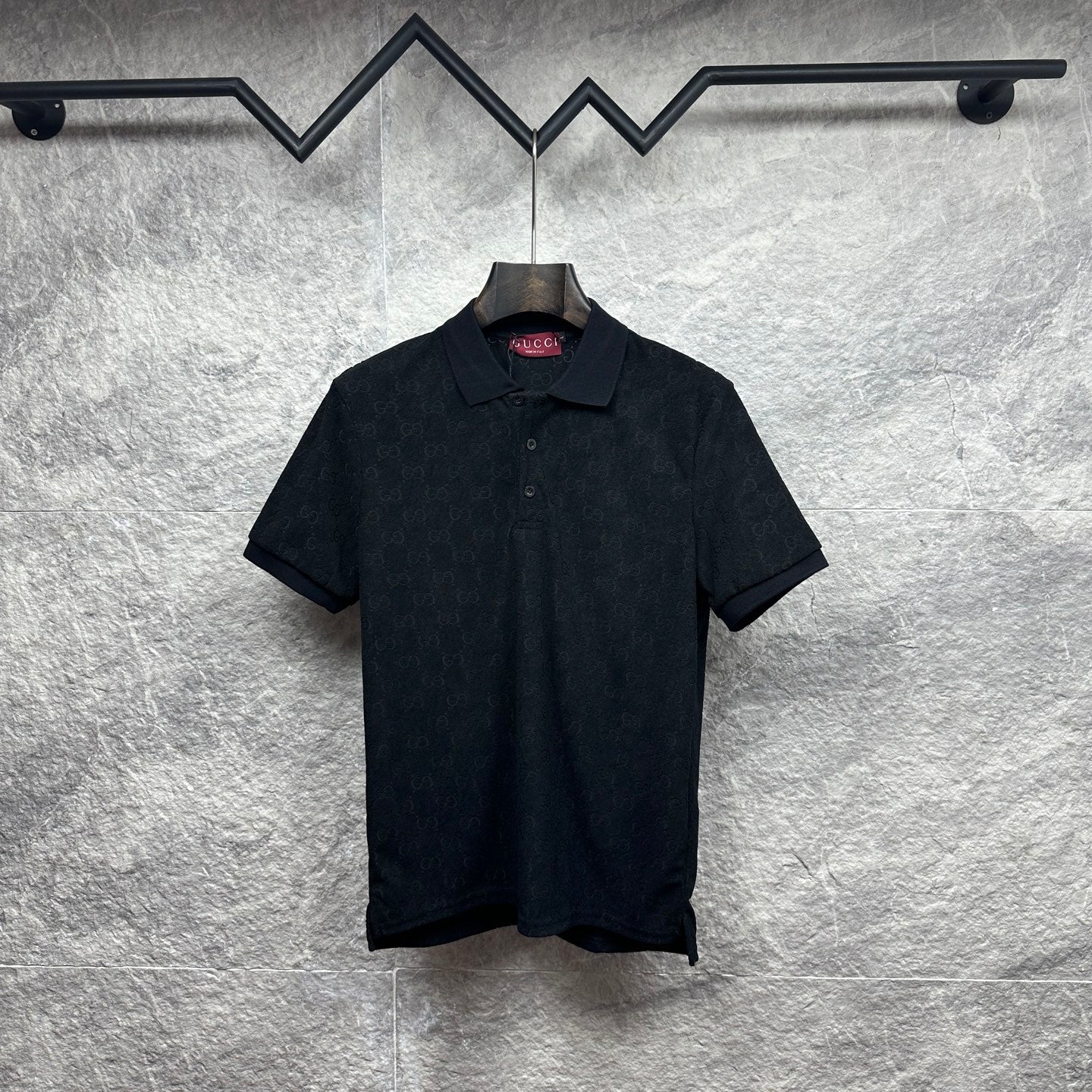 Black Gucci polo shirt, short sleeves, button placket, GG monogram pattern.