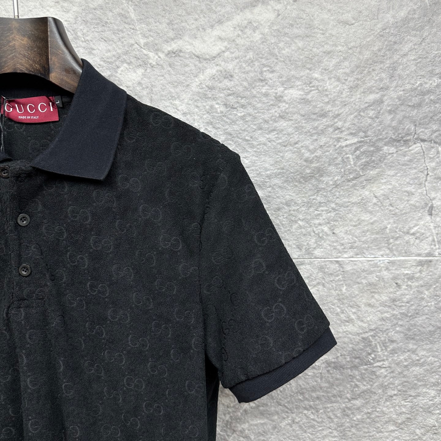 Black Gucci polo shirt, close-up of shoulder and sleeve, GG monogram pattern.