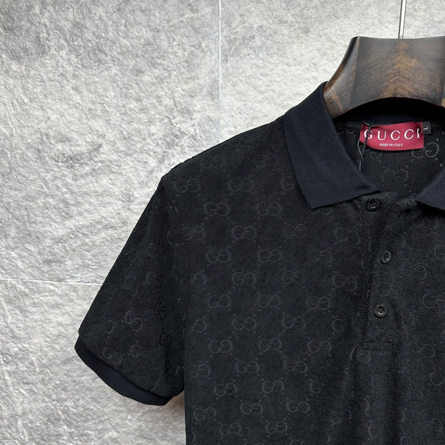 Black Gucci polo shirt, close-up of collar and GG monogram texture.