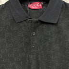 Black Gucci polo shirt neckline close-up, three-button placket, GG monogram.