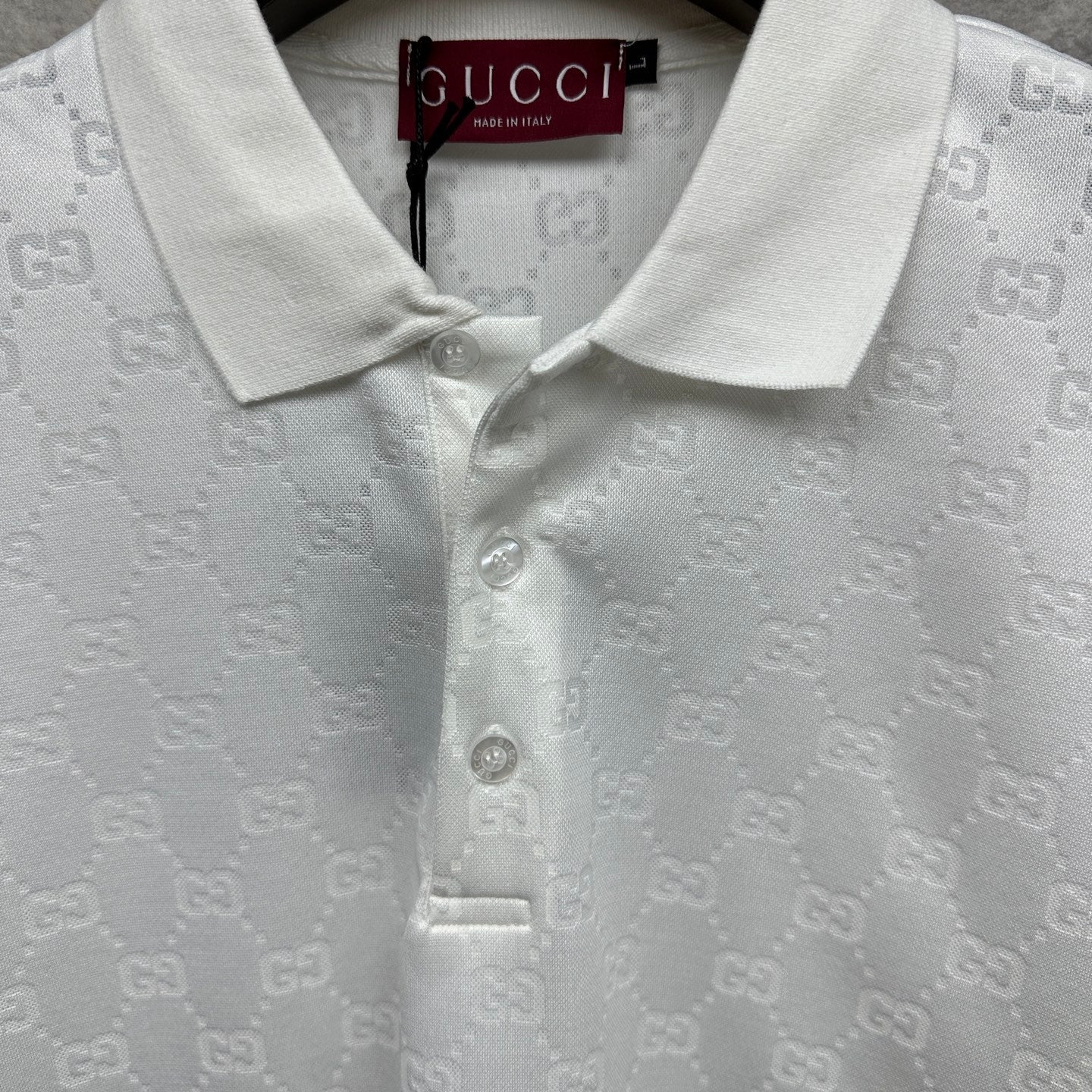 White Gucci polo shirt neckline close-up with GG pattern and buttoned collar