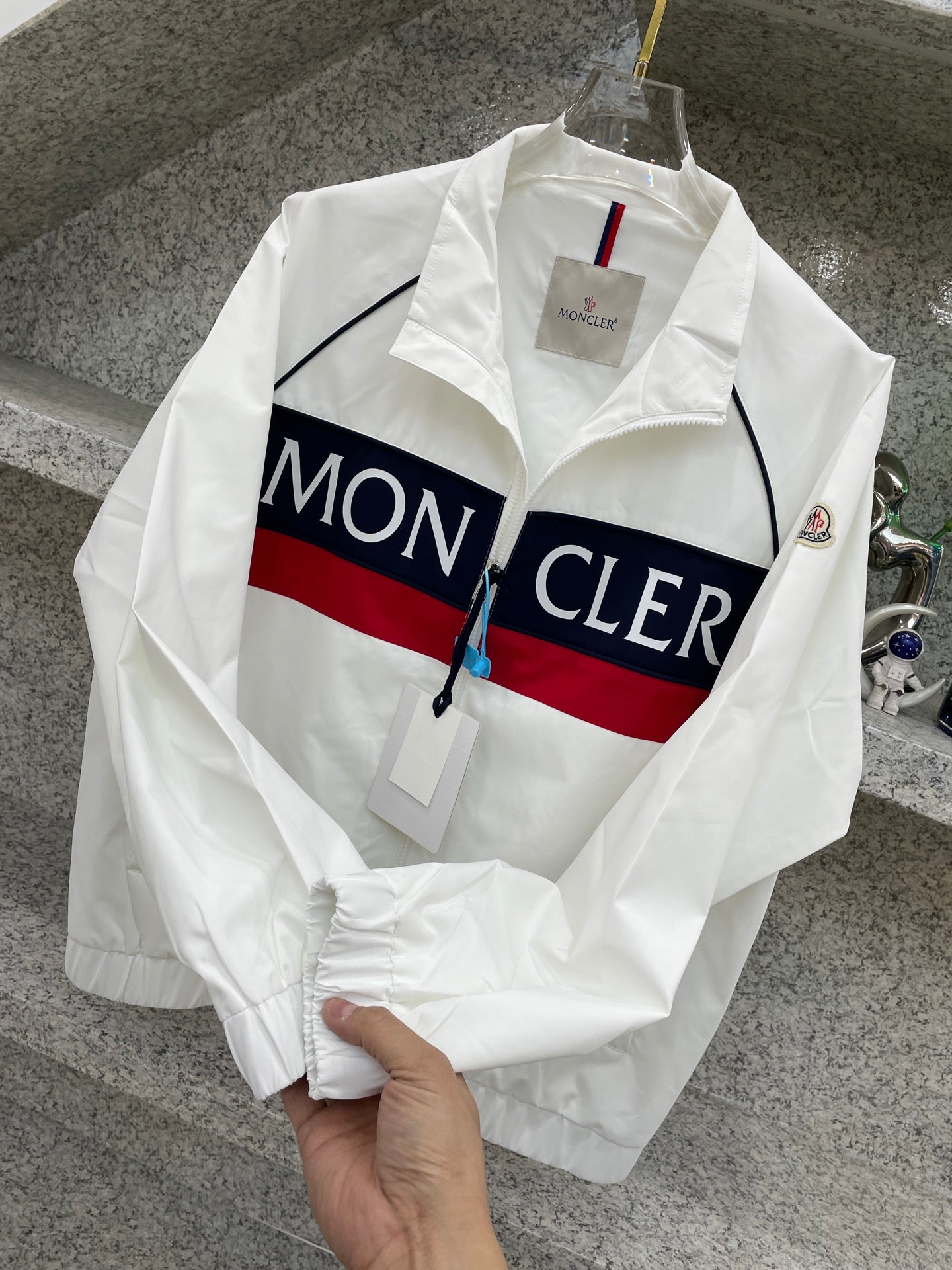 Moncler jacket, white with navy/red logo stripe and zip front on hanger