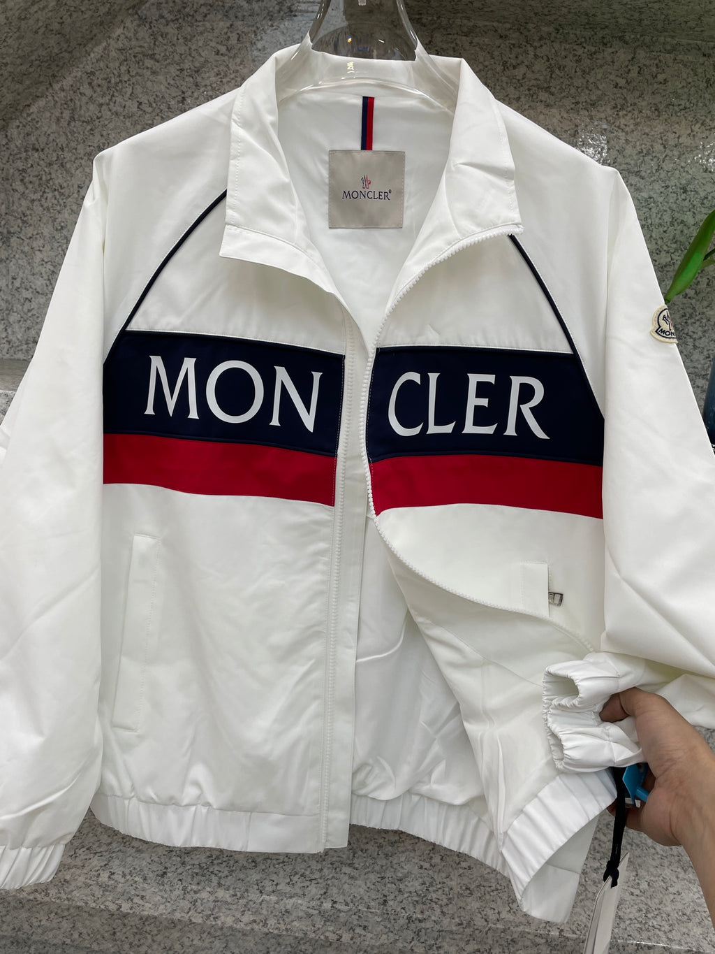 Moncler jacket close-up, white with navy/red logo stripe and zip front