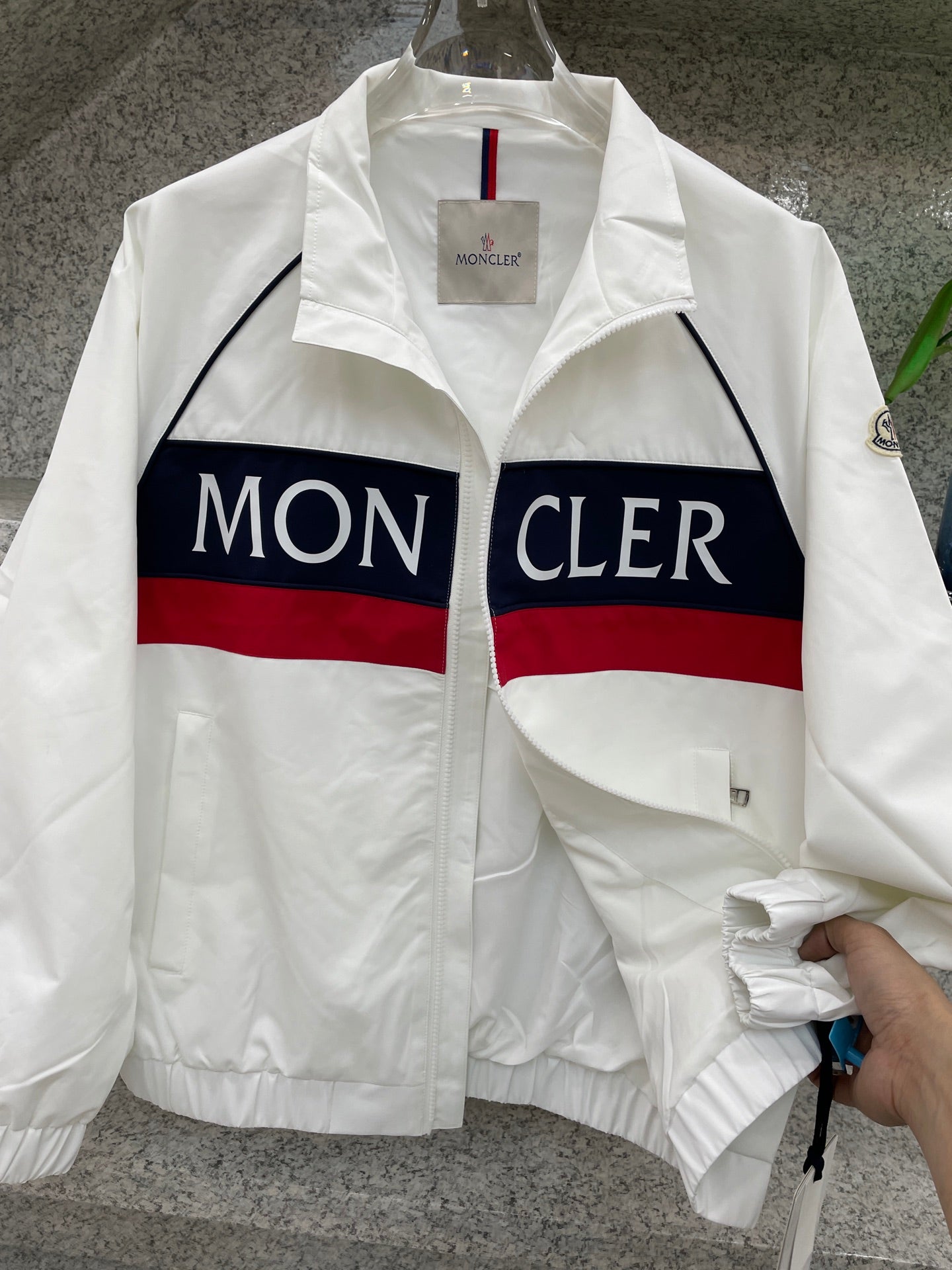 Moncler jacket close-up, white with navy/red logo stripe and zip front