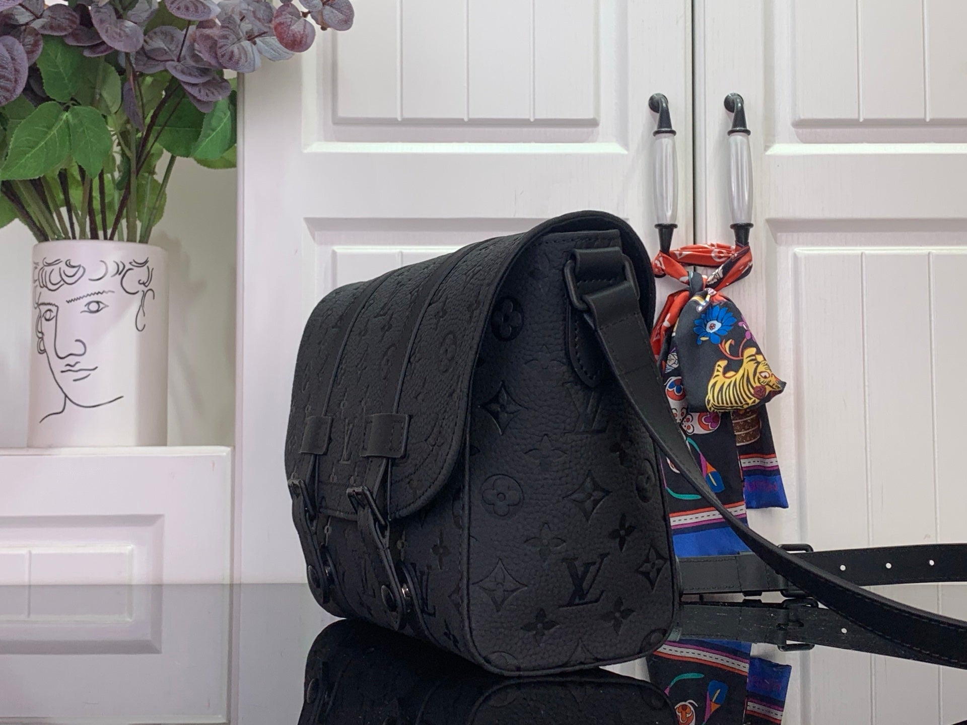Louis Vuitton crossbody bag in dark monogram canvas, side view with adjustable strap