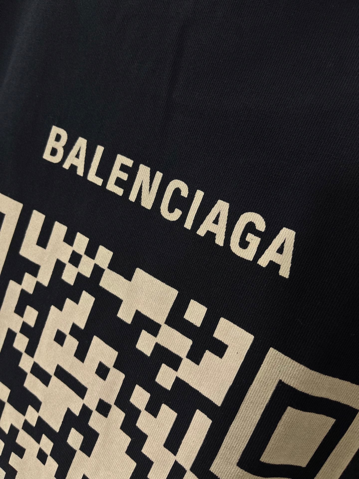 Balenciaga T-shirt close-up showing large “BALENCIAGA” lettering over pixel pattern