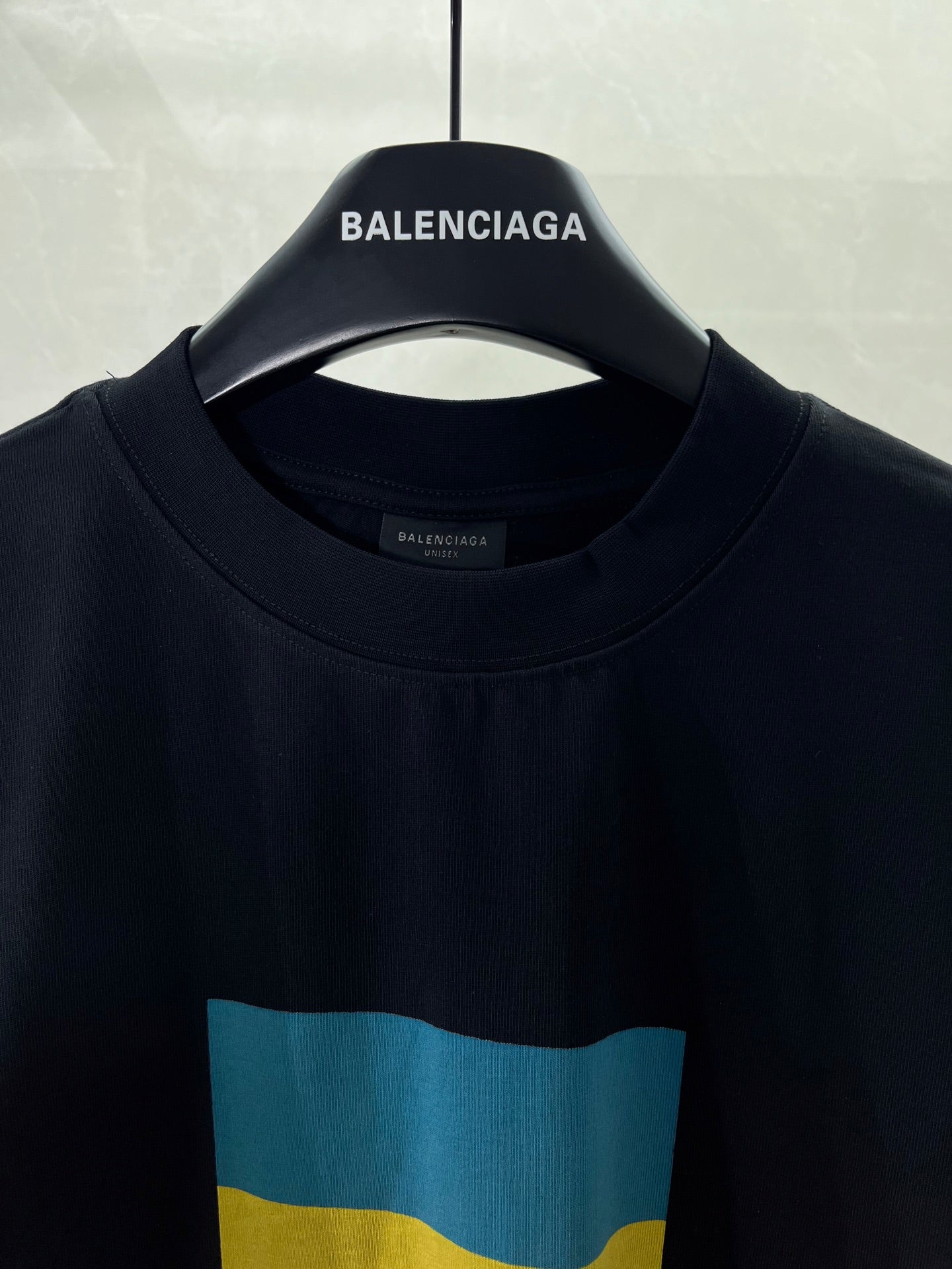 Balenciaga crew-neck T-shirt close-up with “BALENCIAGA” and blue-yellow flag print
