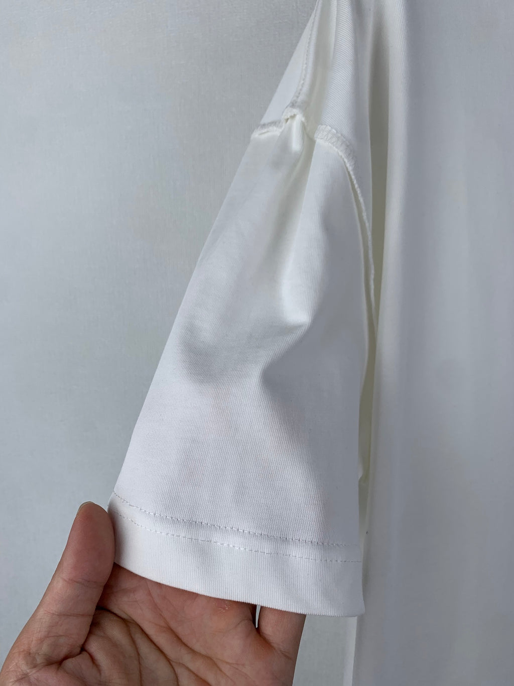 White T-shirt sleeve with stitched cuff and side seam detail.
