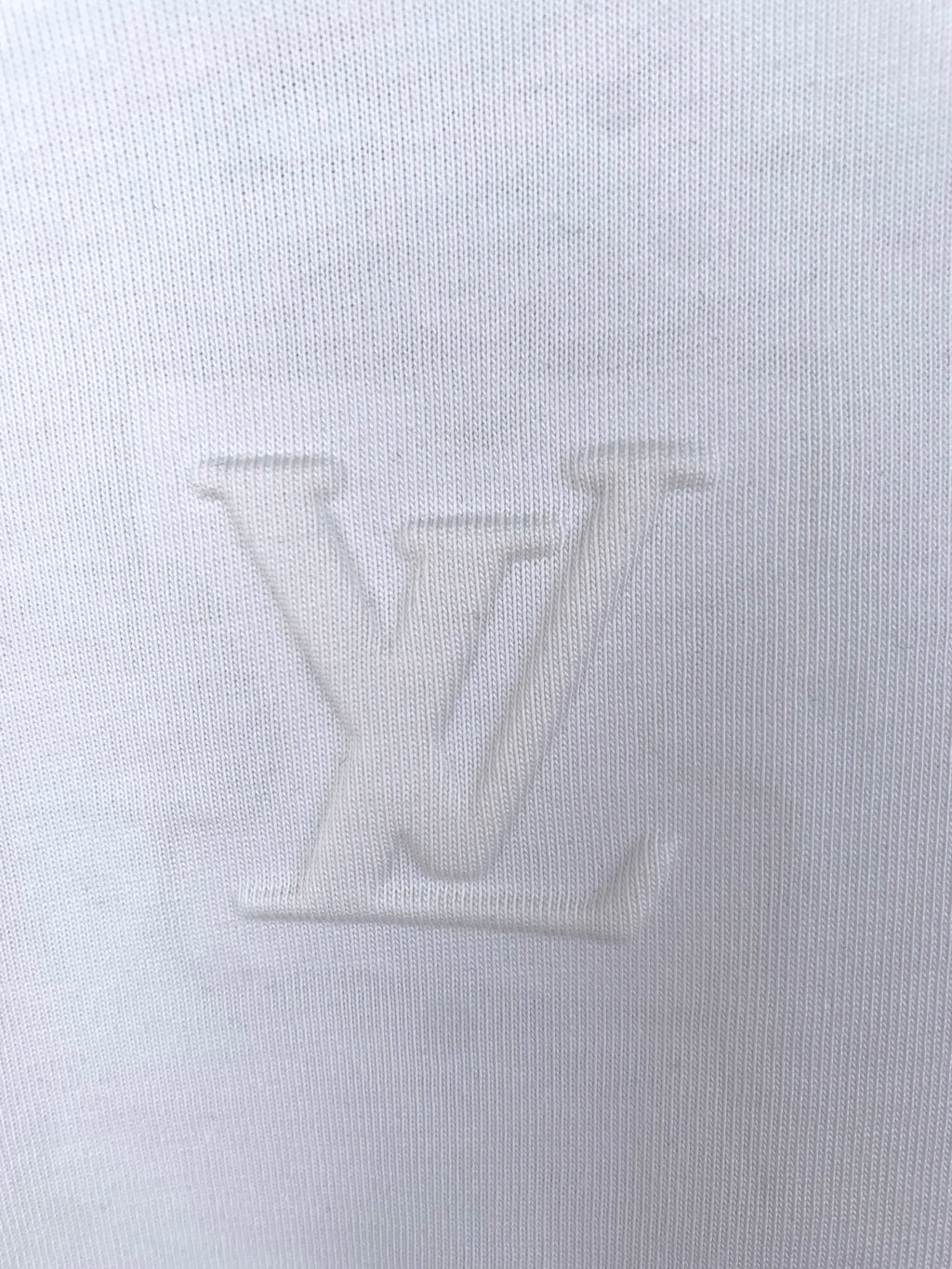 White knit T-shirt fabric close-up, showing fine weave texture.