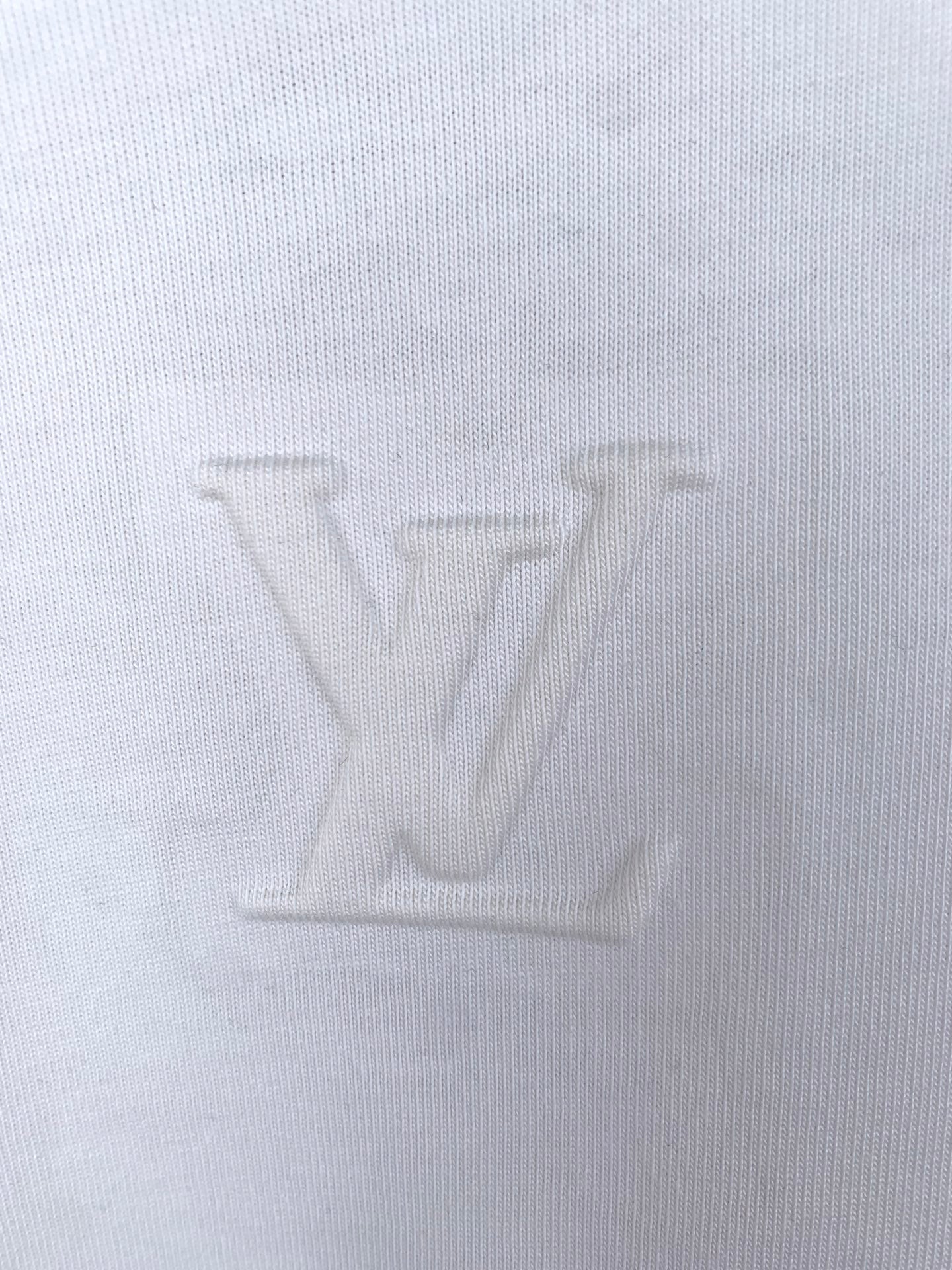White knit T-shirt fabric close-up, showing fine weave texture.