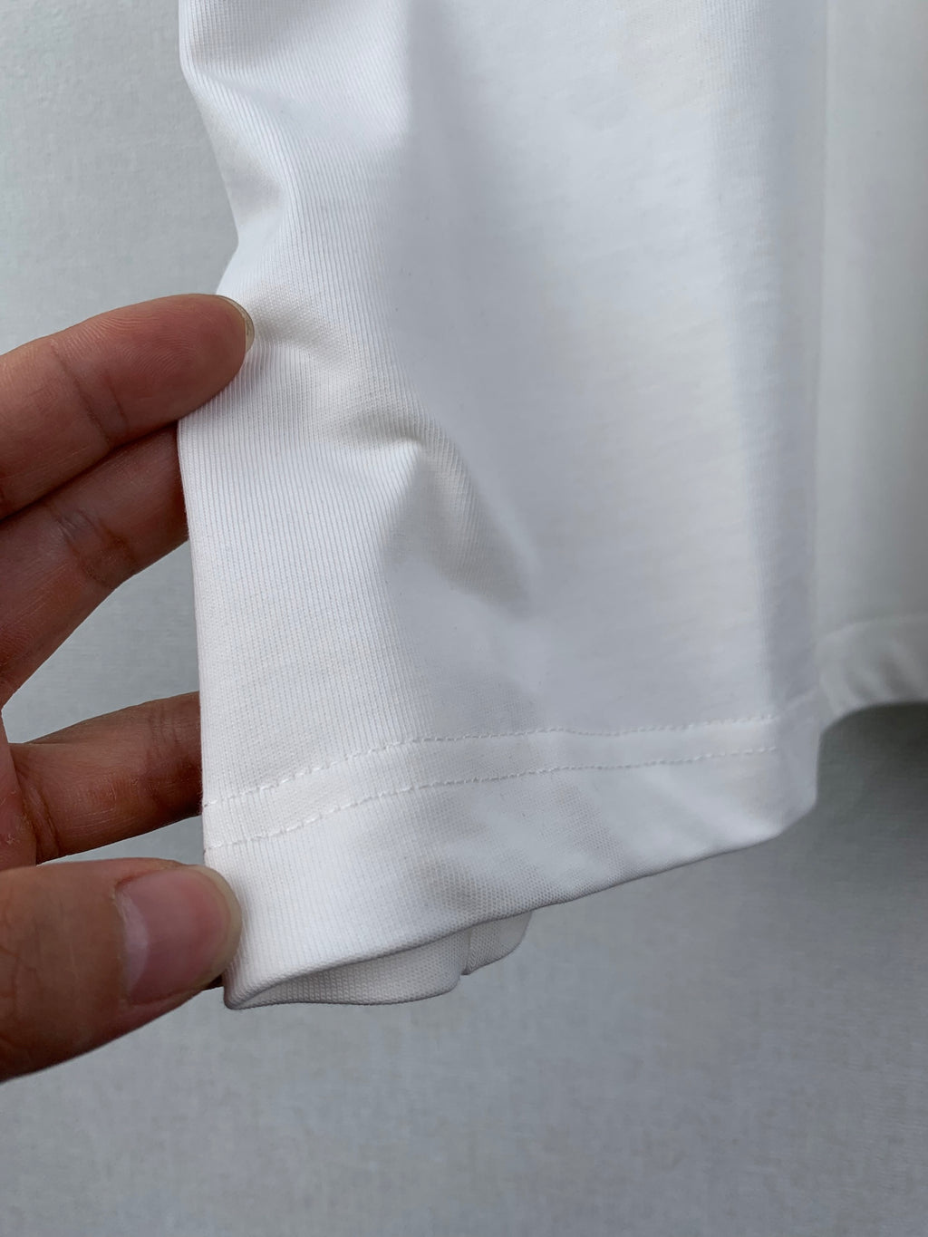 White T-shirt hem with stitched seam detail near side.