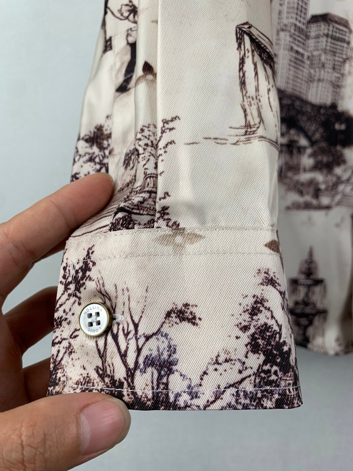 White printed button-up shirt sleeve cuff with round dark logo-style button