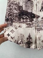 White printed button-up shirt placket detail with dark building and emblem motifs