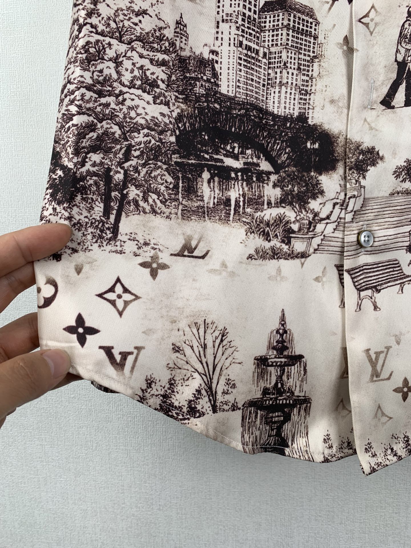 White printed button-up shirt placket detail with dark building and emblem motifs