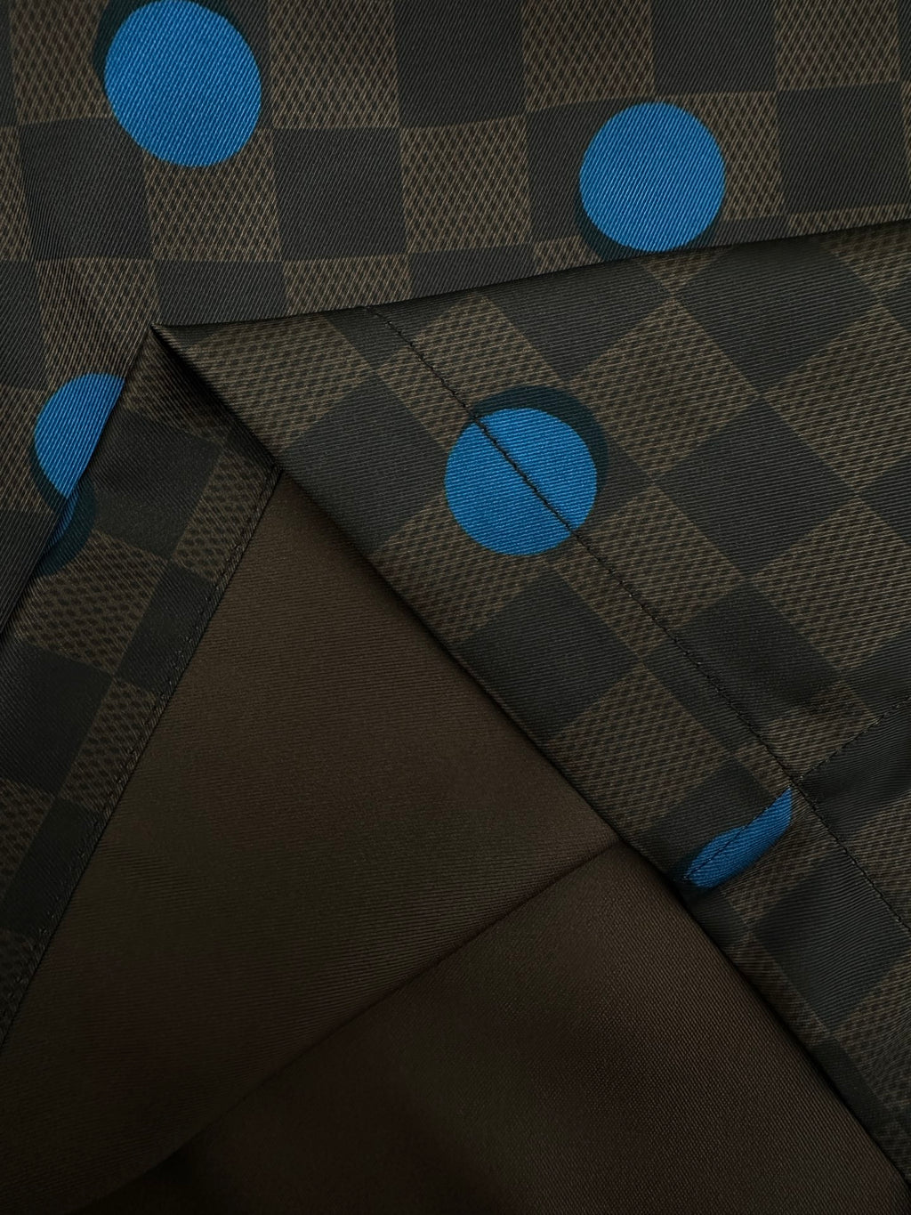 Close-up of brown shorts fabric with blue dot and check pattern