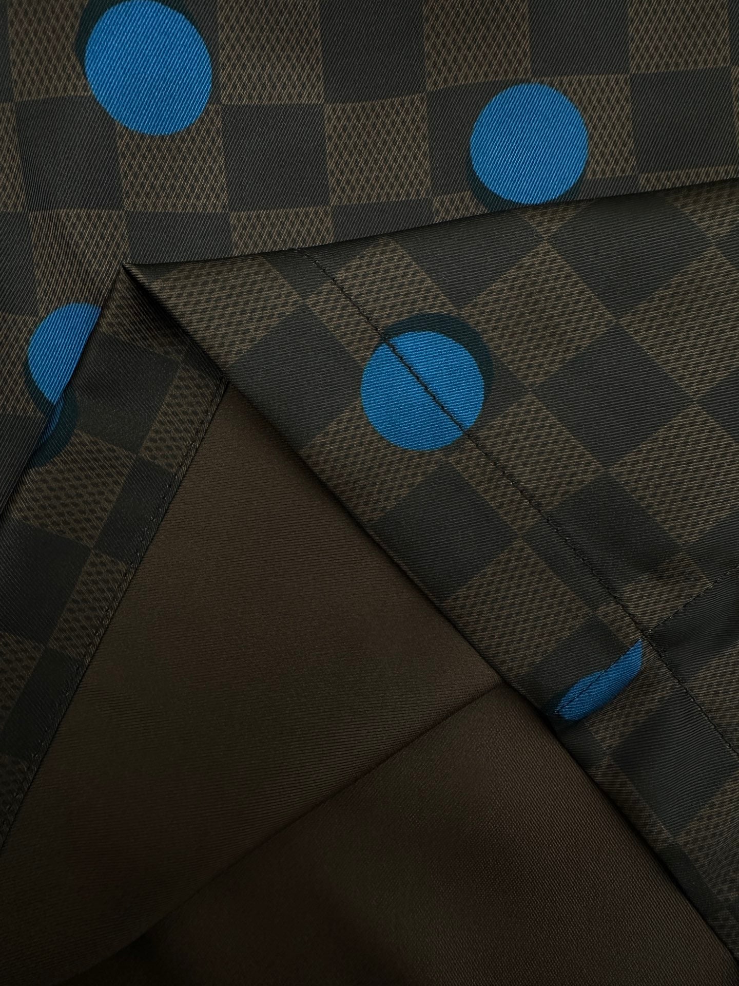 Close-up of brown shorts fabric with blue dot and check pattern