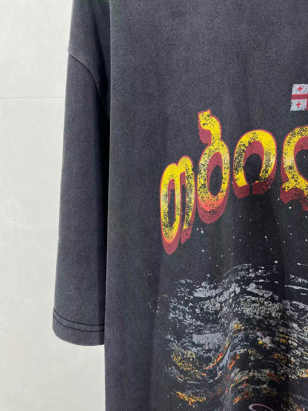 Dark blue T-shirt front with yellow and pink logo graphic and paint splatter