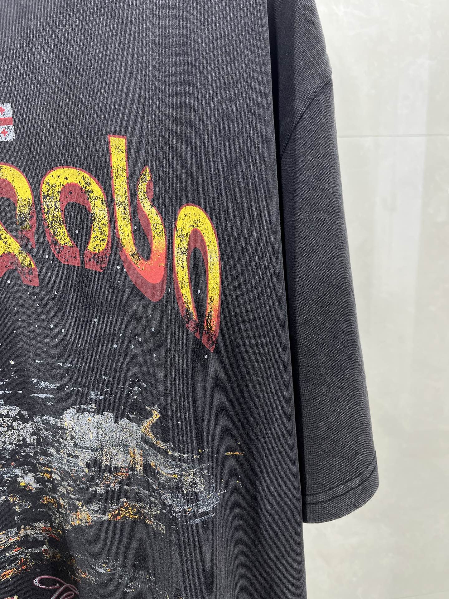 Dark blue T-shirt sleeve and large yellow-red lettering graphic