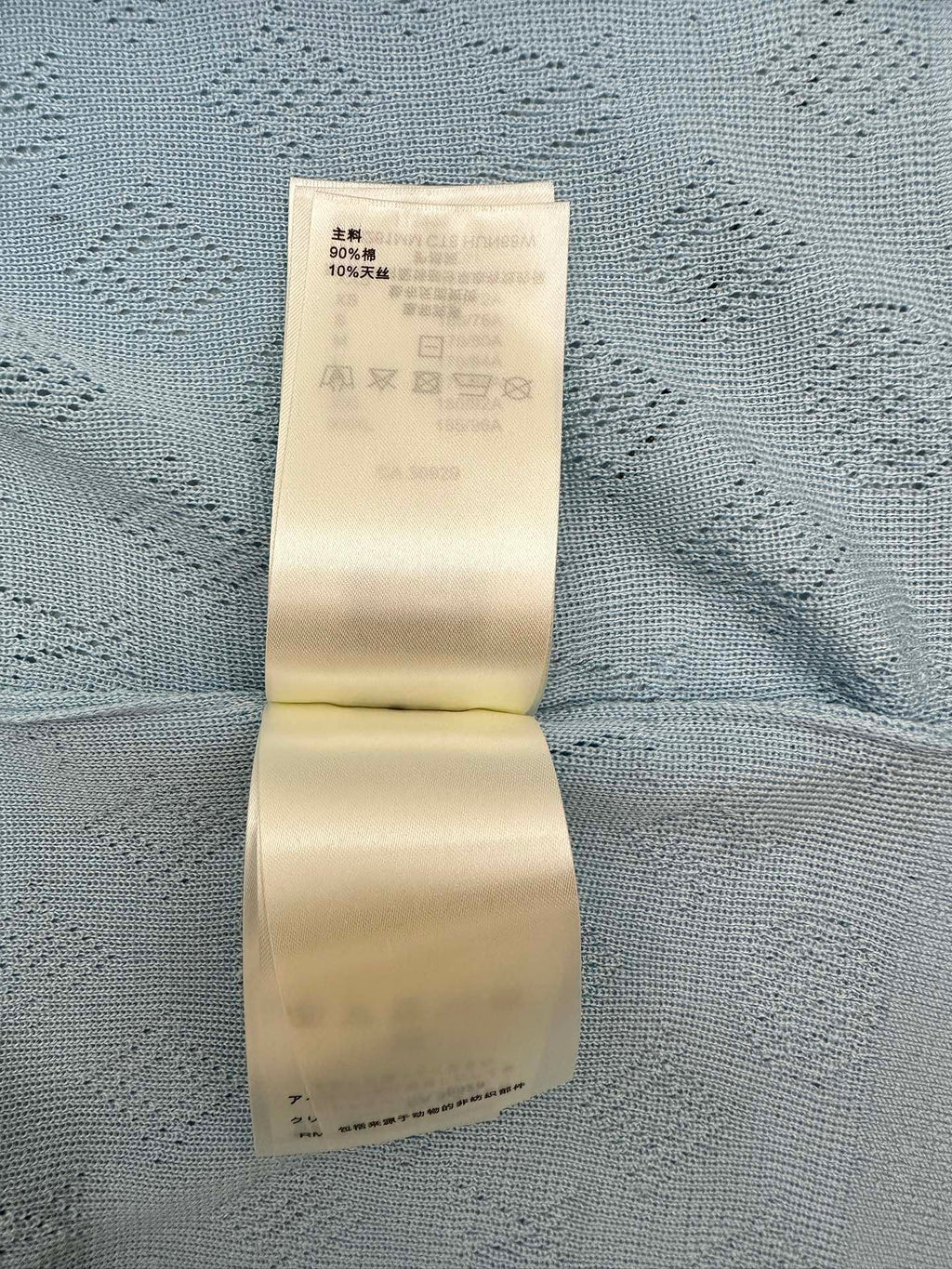 Light blue polo shirt fabric with care instructions label