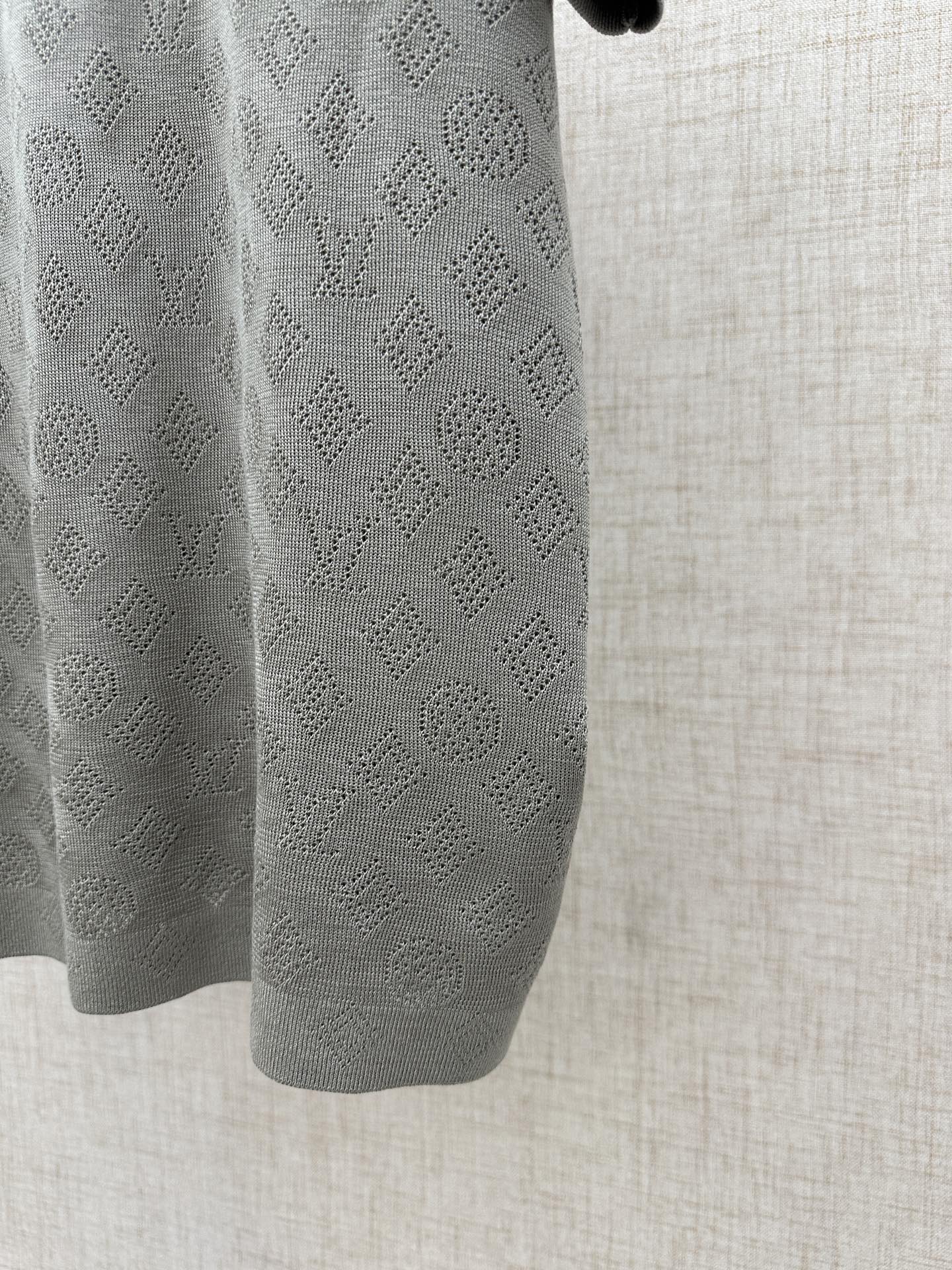 Light gray polo shirt sleeve with repeating monogram knit texture