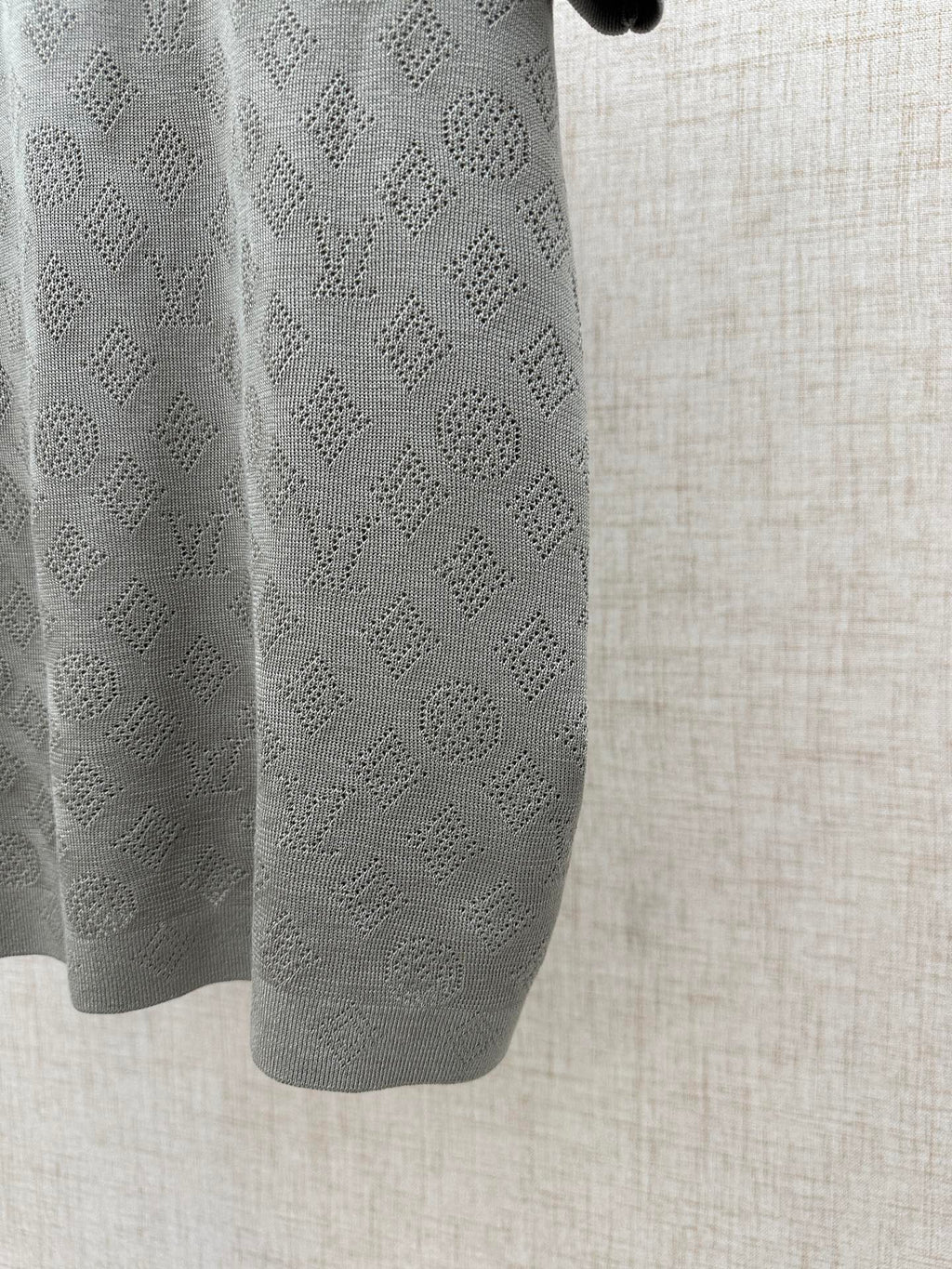 Gray polo side close-up with patterned knit texture and curved hem