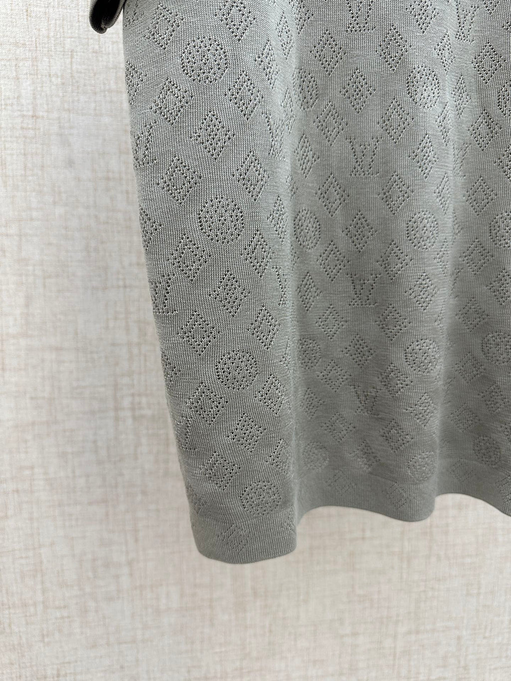 Light gray polo shirt fabric close-up with repeating monogram pattern
